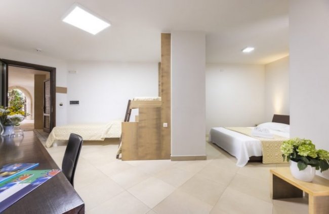 Camera spaziosa con letto e letti a castello.
