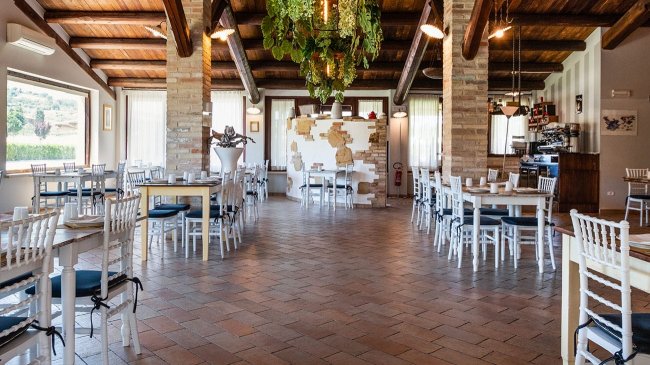 Ristorante interno con tavoli e sedie bianche.