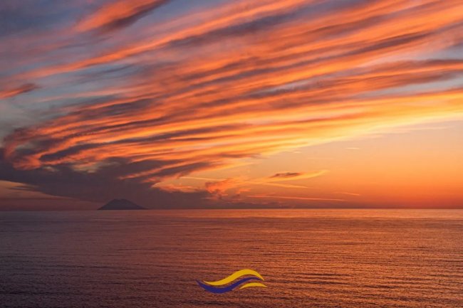 Tramonto con nuvole colorate sopra il mare.