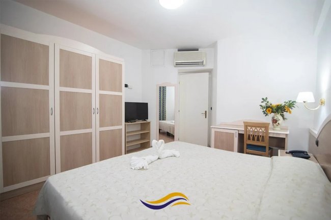 Camera da letto con armadio, TV e scrivania.
