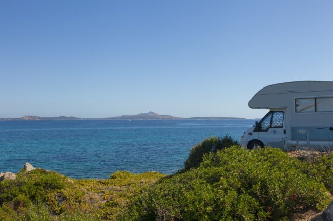 Un camper vicino al mare con panorama di isole in lontananza.