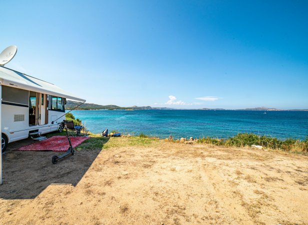 Camper parcheggiato vicino a una spiaggia con vista sull'oceano.