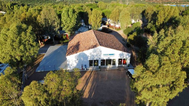 Edificio bianco circondato da alberi, tetto marrone.