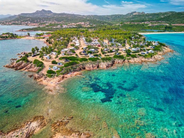 Isola rocciosa circondata da mare cristallino e campeggi.