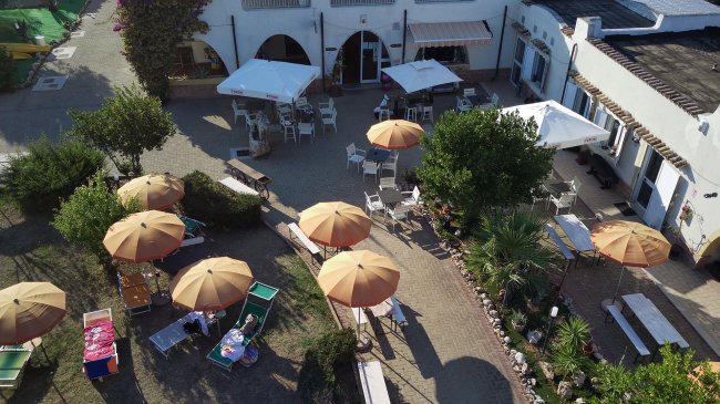 Giardino con ombrelloni e tavolini all'aperto.