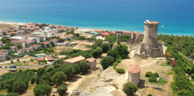 Veduta aerea di un'area costiera con rovine storiche e il mare sullo sfondo.