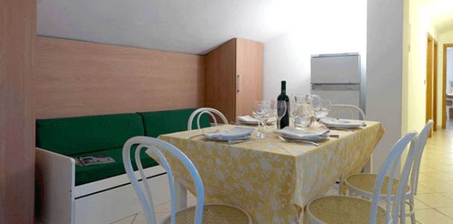 Tavolo apparecchiato in una sala da pranzo con sedie bianche.