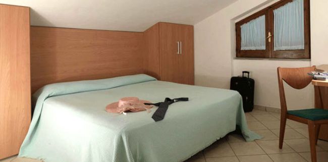 Una camera con letto matrimoniale e valigia.