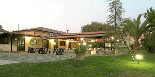 Esterno di un ristorante con tavoli all'aperto e giardino.
