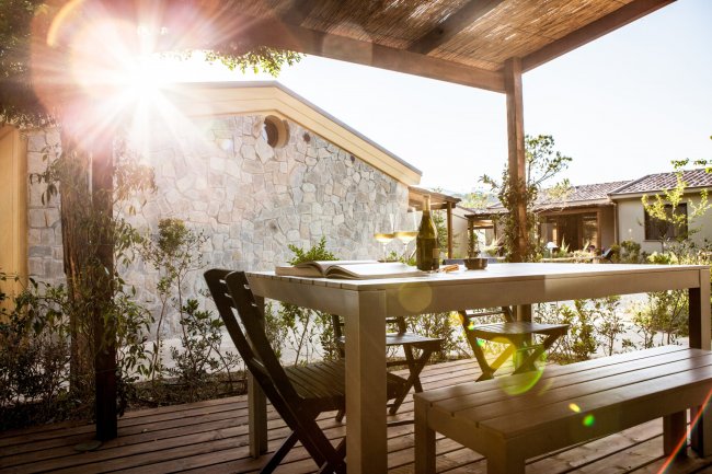 Tavolo all'aperto sotto pergola con sole splendente.