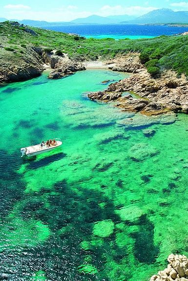 Barca su acqua verde cristallina circondata da costa rocciosa.