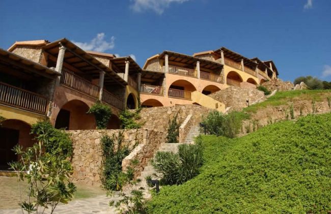 Complesso residenziale con archi e pietra, situato su una collina verde.