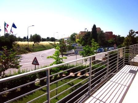 Vista dalla ringhiera su una strada con segnali, automobili e vegetazione.