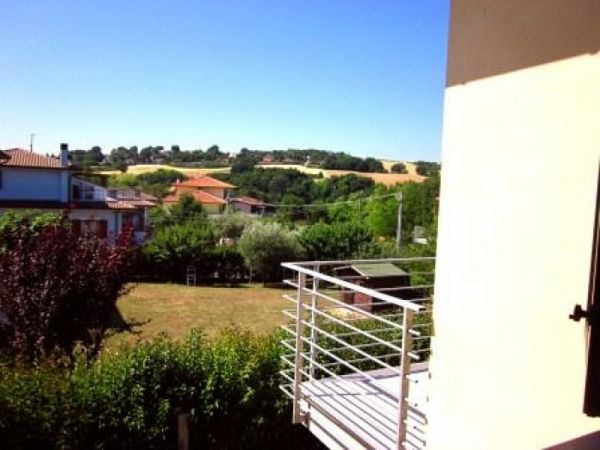 Veduta panoramica di campagna con case e vegetazione.