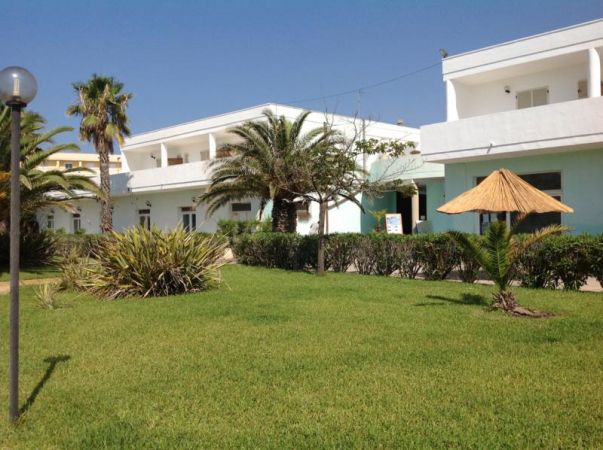 Edificio bianco e giardino con palme.