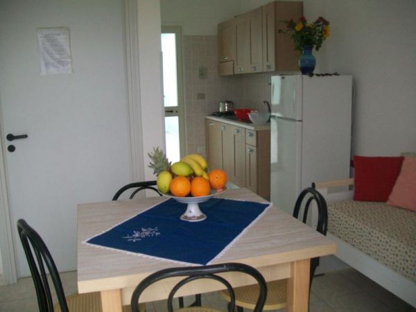Tavolo con frutta, cucina in legno, ambiente luminoso.