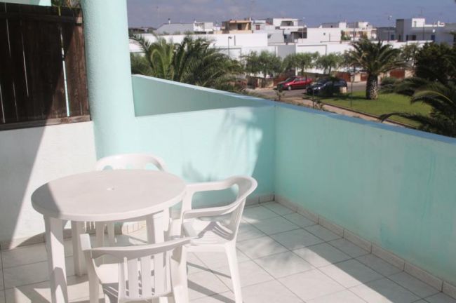 Balcone con tavolo, sedie e vista su palme.