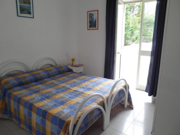 Letto matrimoniale con copriletto a quadri in stanza luminosa.
