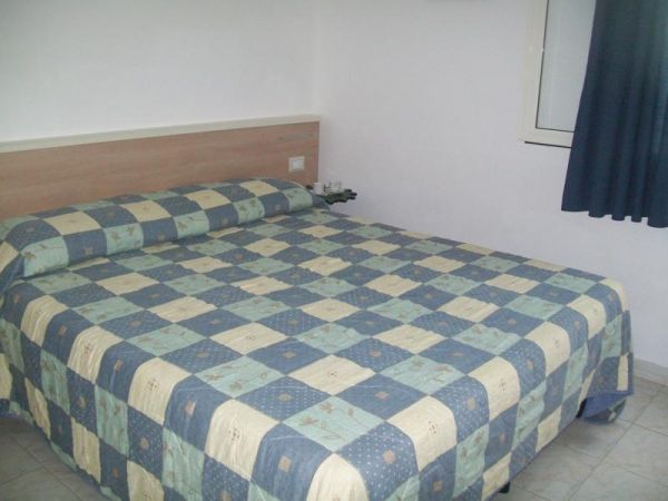 Letto matrimoniale con copriletto a scacchi blu e beige.