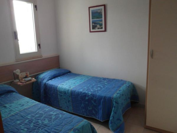 Due letti singoli con copriletti blu in piccola stanza.