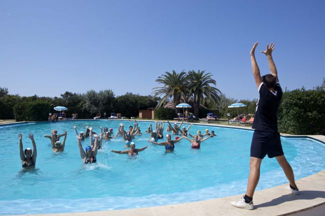 Istruttrice guida una lezione di aquagym in una piscina all'aperto.