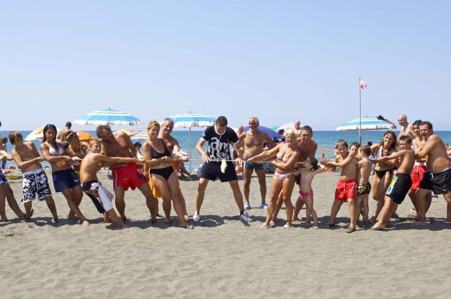 Gruppo di persone impegnate in un tiro alla fune sulla spiaggia.