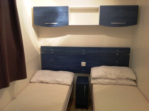 Due letti singoli affiancati con un mobile azzurro sopra di essi.