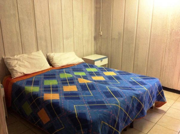 Camera con letto matrimoniale e copriletto colorato, comodino a fianco.