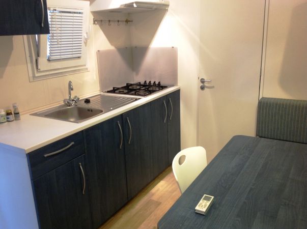 Cucina compatta con lavabo, piano cottura e tavolo.
