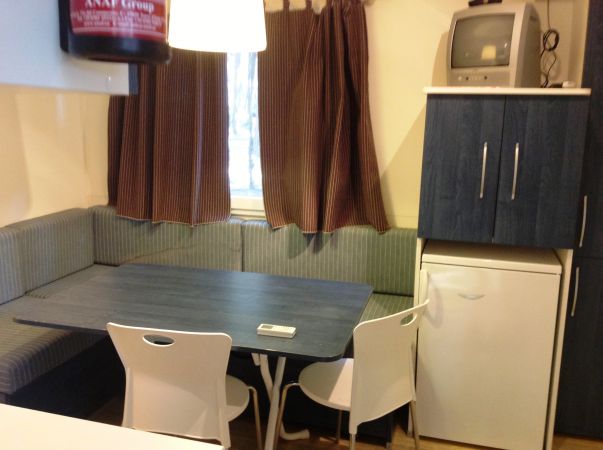 Sala da pranzo con tavolo, sedie e divano angolare.