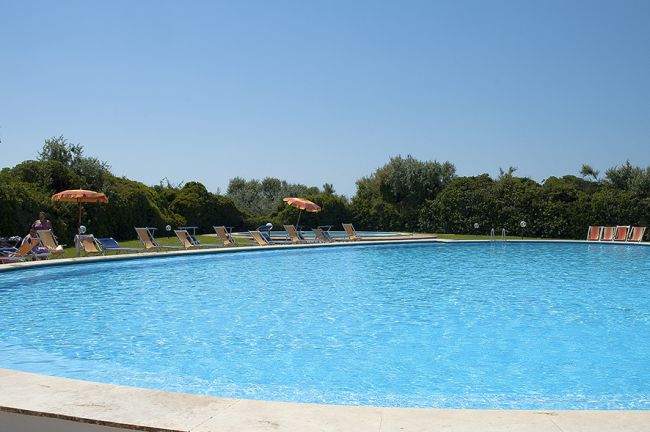 Piscina all'aperto con lettini e ombrelloni arancioni.
