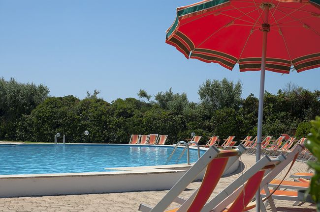 Lettini e ombrelloni arancioni a bordo piscina.