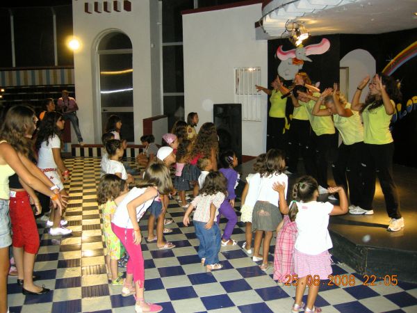 Bambini danzano di fronte a un palco con animatori.
