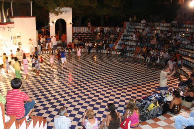 Folla in un anfiteatro all'aperto osserva bambini che giocano.