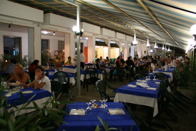 Ristorante all'aperto con tavoli apparecchiati di blu.