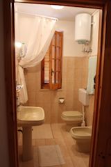 Bagno beige con doccia, lavandino e bidet.