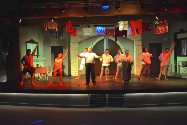 Spettacolo teatrale con attori che ballano sul palco.