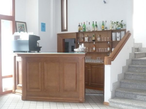 Una reception in legno con bottiglie e bicchieri su uno scaffale alle spalle.