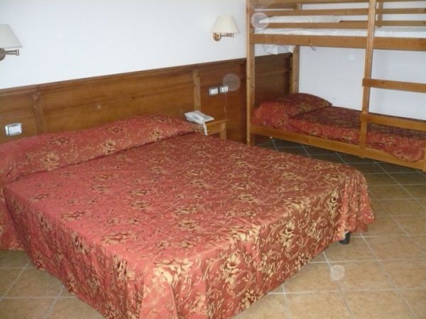 Camera da letto con letto matrimoniale e un letto a castello, copriletti rossi.