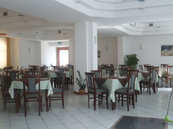 Sala ristorante spaziosa con tavoli apparecchiati e sedie in legno scuro.