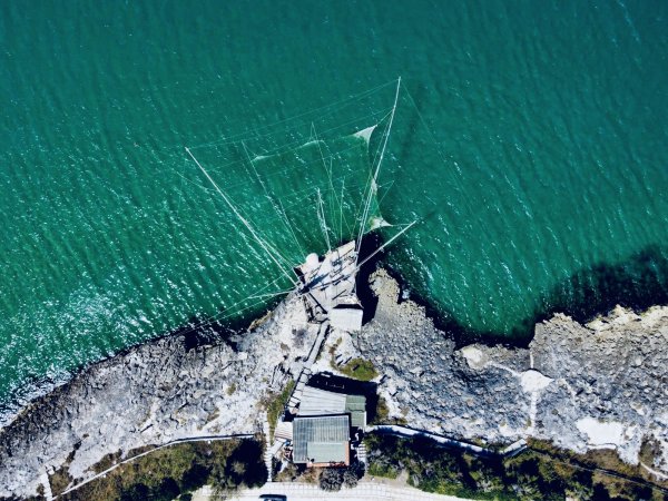 Veduta aerea di una struttura con reti su una costa rocciosa.