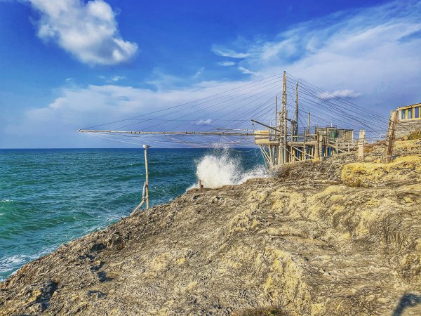Struttura di legno sul mare con onde che si infrangono sulle rocce.