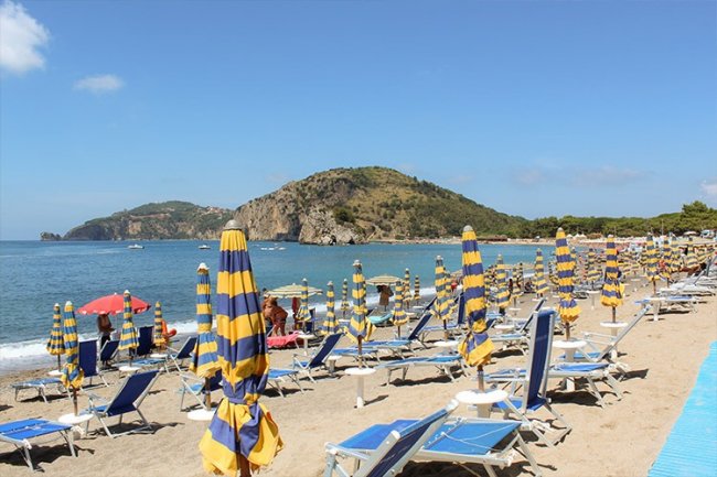 Spiaggia con ombrelloni gialloblù e lettini.