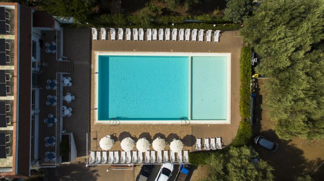 Vista aerea di una piscina con lettini e ombrelloni.