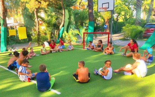 Bambini seduti in cerchio su campo da gioco.