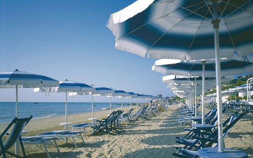 Spiaggia con ombrelloni blu e lettini.