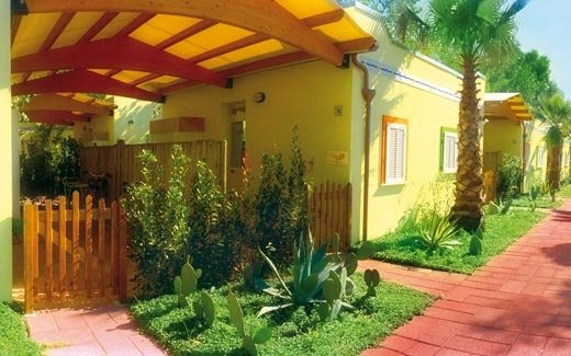 Villino giallo con giardino e palme.