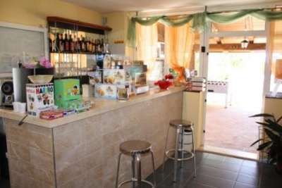 Bancone bar con sgabelli, snack confezionati e uscite verso l'esterno.