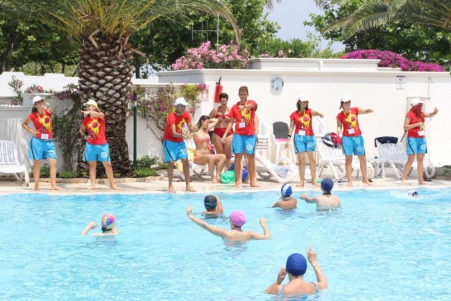 Animatori in piscina con bambini che giocano.