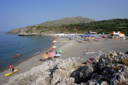 Vista di una spiaggia affollata con ombrelloni colorati e mare calmo.